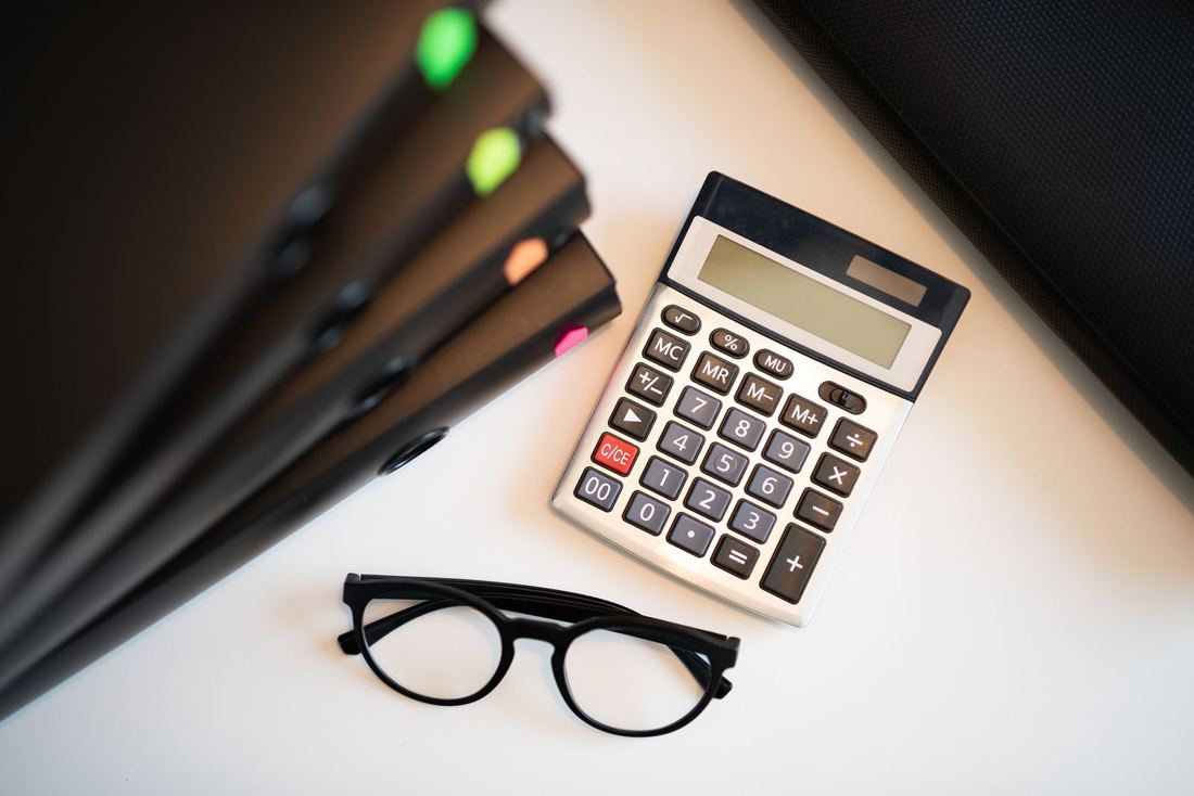 Calculadora, pastas e óculos sobre uma mesa organizada